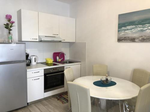 a kitchen with a table and a white refrigerator at Apartments by the sea Kozarica, Mljet - 4950 in Kozarica