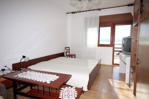 1 dormitorio con cama, mesa y TV en Apartments with a parking space Lokva Rogoznica, Omis - 4819 en Lokva Rogoznica