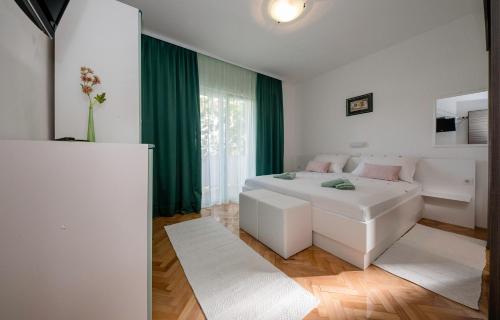 1 dormitorio con cama blanca y cortina verde en Apartments with a parking space Palit, Rab - 4971, en Rab