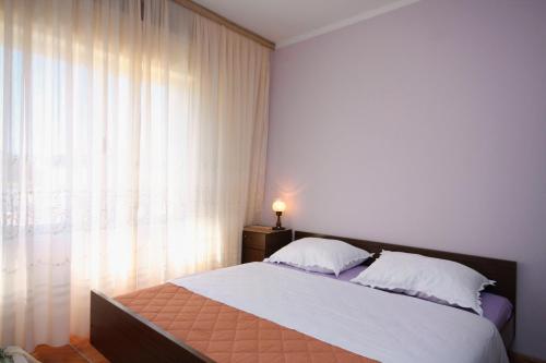 a bedroom with a large bed and a window at Apartments by the sea Supetarska Draga - Donja, Rab - 4981 in Supetarska Draga