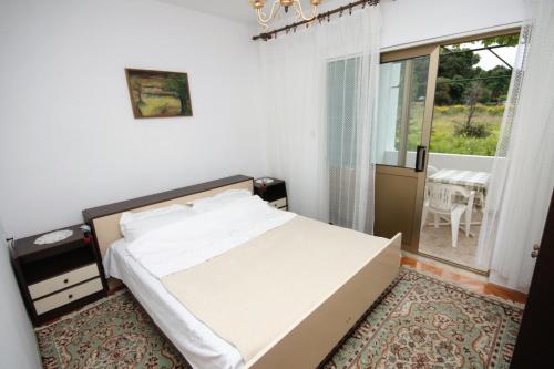a small bedroom with a bed and a window at Apartments by the sea Supetarska Draga - Gonar, Rab - 4989 in Supetarska Draga