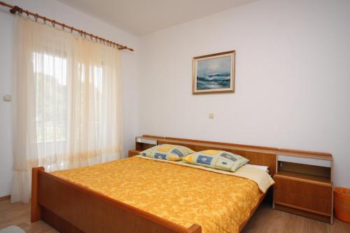 una camera da letto con un letto con lenzuola gialle e una finestra di Apartments by the sea Kampor, Rab - 4986 a Rab