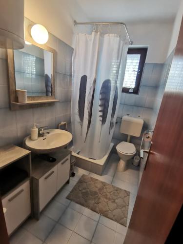 a bathroom with a shower curtain and a toilet at Apartments by the sea Barbat, Rab - 4975 in Rab