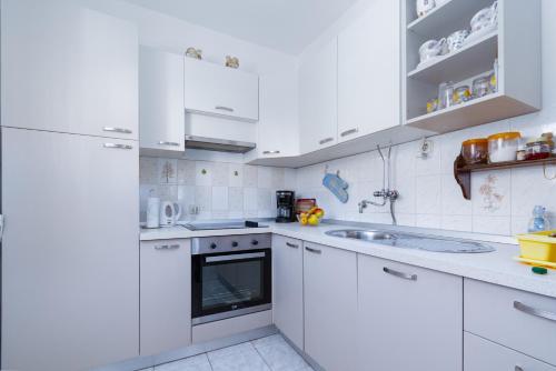 eine weiße Küche mit weißen Schränken und einer Spüle in der Unterkunft Apartments by the sea Barbat, Rab - 4977 in Barbat na Rabu