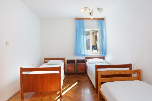Cette chambre comprend 3 lits et une fenêtre. dans l'établissement Family friendly apartments with a swimming pool Podstrana, Split - 4859, à Podstrana