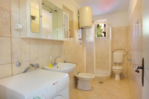 La salle de bains est pourvue d'un lavabo et de toilettes. dans l'établissement Family friendly apartments with a swimming pool Podstrana, Split - 4859, à Podstrana
