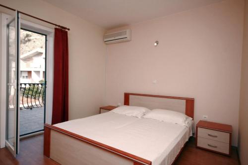 een slaapkamer met een bed en een glazen schuifdeur bij Apartments by the sea Duce, Omis - 4852 in Duće