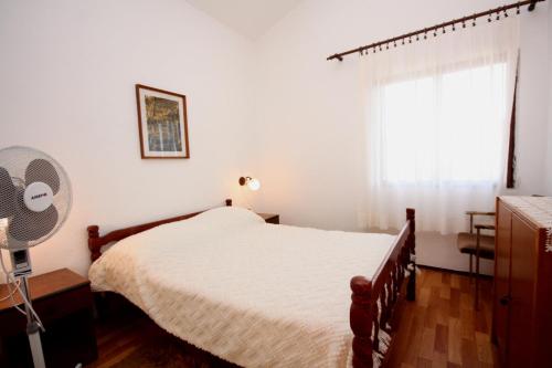 a bedroom with a bed and a window with a fan at Apartments by the sea Sevid, Trogir - 5221 in Sevid