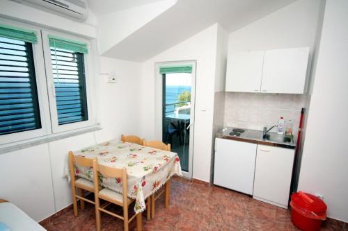 a kitchen with a table and chairs in a room at Apartments by the sea Balica Rat, Omis - 4868 in Čelina