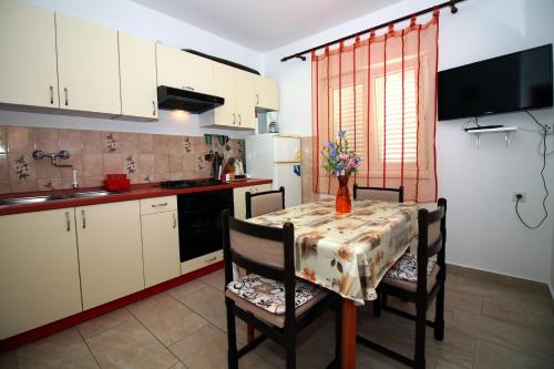 a kitchen with a table and chairs and a kitchen with white cabinets at Apartments by the sea Tisno, Murter - 5136 in Tisno