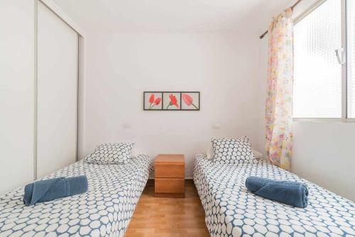 2 camas individuais num quarto com paredes brancas em Primera línea con preciosas vistas al mar em Melenara
