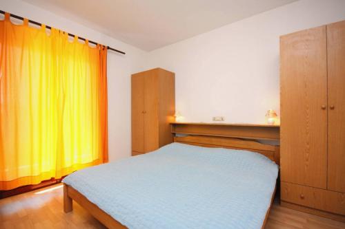 a bedroom with a bed and a yellow curtain at Apartments and rooms by the sea Palit, Rab - 5044 in Rab