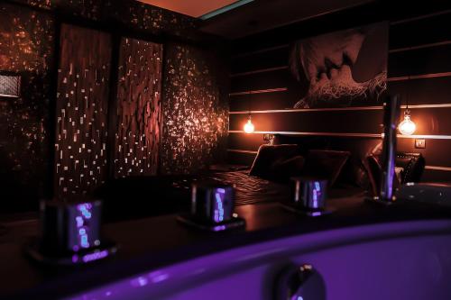 um quarto escuro com luzes roxas na parede em La suite détendue em Saint-Blimont