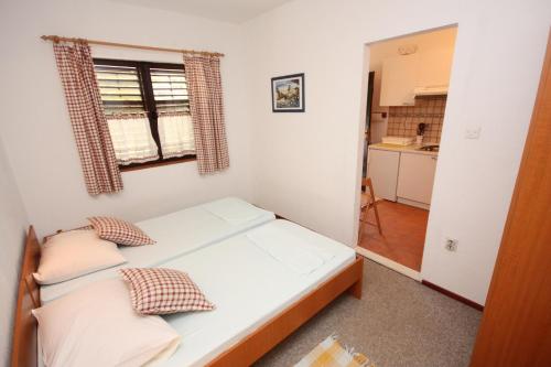 małą sypialnię z łóżkiem i kuchnią w obiekcie Family friendly apartments with a swimming pool Maslinica, Solta - 5180 w mieście Maslinica