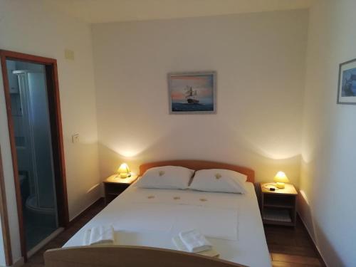Apartments by the sea Cove Saplunara, Mljet - 4896 في Maranovići: غرفة نوم بسرير ابيض ومصباحين