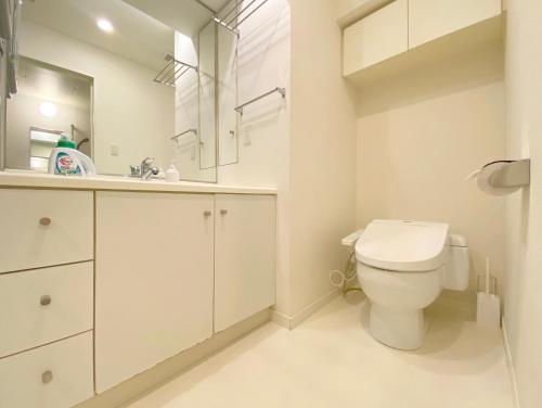 a white bathroom with a toilet and a sink at Pangoo Shinagawa in Tokyo