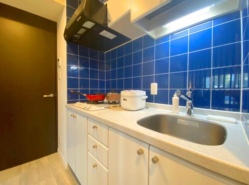 a kitchen with a sink and a blue tiled wall at Pangoo Shinagawa in Tokyo