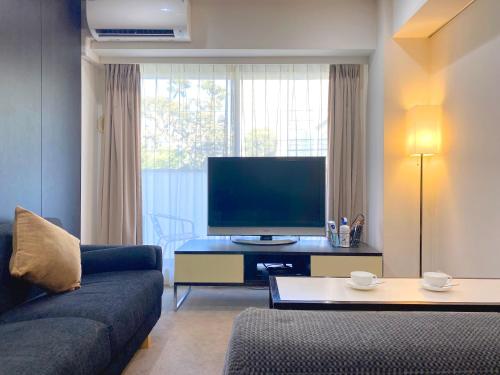 a living room with a couch and a flat screen tv at Pangoo Shinagawa in Tokyo