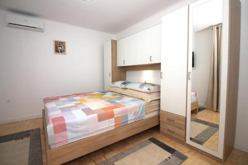 a bedroom with a bed and a mirror at Family friendly apartments with a swimming pool Tisno, Murter - 5073 in Tisno