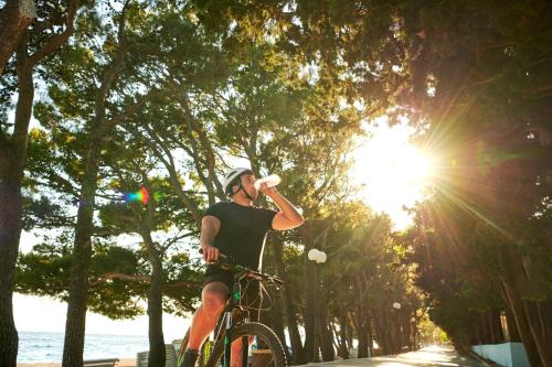 a man riding a bike while drinking a beverage at Bluesun Holiday Village Afrodita in Tučepi