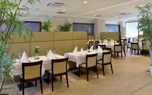 a restaurant with white tables and chairs and plants at Flamingo Grand Hotel & Spa in Albena