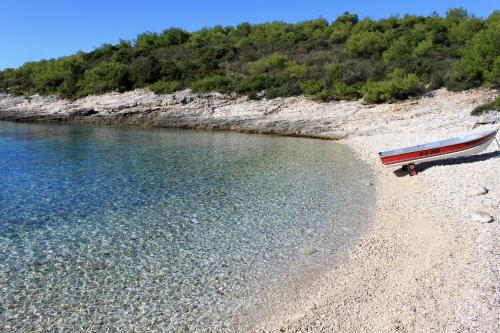 a boat sitting on a beach next to the water at Apartments with parking space Rukavac, Vis - 8839 in Rukavac