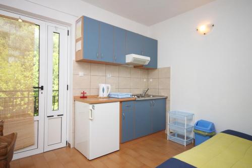 a small kitchen with blue cabinets and a table at Apartments with a parking space Zivogosce - Porat, Makarska - 6700 in Igrane