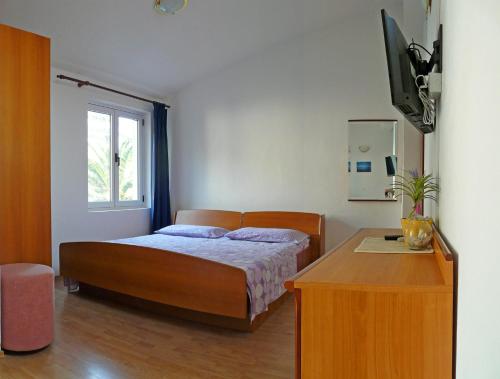 a bedroom with a bed and a table and a television at Apartments by the sea Drvenik Donja vala, Makarska - 6756 in Drvenik
