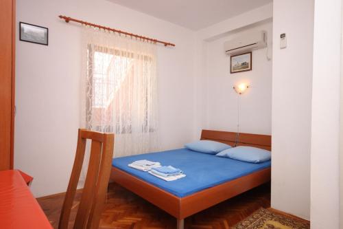 a small bedroom with a blue bed and a window at Apartments by the sea Maslenica, Novigrad - 6568 in Jasenice