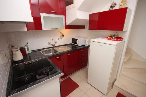 a small kitchen with red cabinets and a white refrigerator at Apartments with a parking space Brela, Makarska - 6884 in Brela