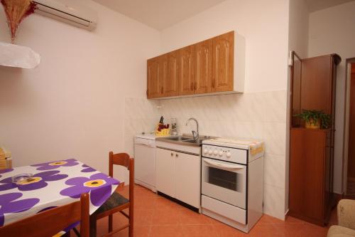 eine Küche mit einem Tisch, einer Spüle und einem Herd in der Unterkunft Apartments by the sea Maslenica, Novigrad - 6568 in Jasenice