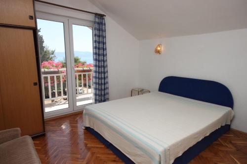 um quarto com uma cama e uma janela com uma varanda em Apartments by the sea Brist, Makarska - 6813 em Brist