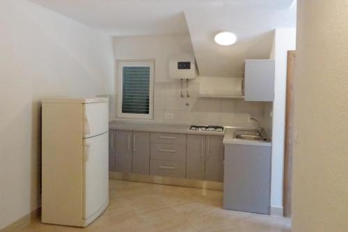 uma cozinha com um frigorífico branco e um lavatório em Apartments by the sea Brist, Makarska - 6813 em Brist