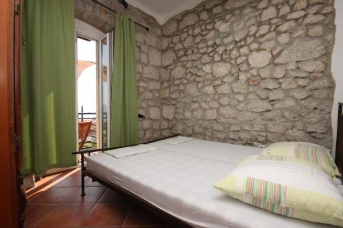 a bed in a room with a stone wall at Apartments by the sea Gradac, Makarska - 6661 in Gradac