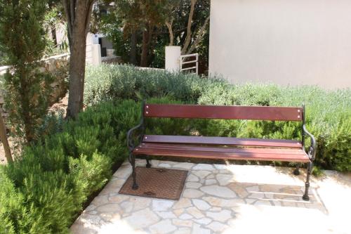 a wooden bench sitting on a stone walk way at Apartments by the sea Mandre, Pag - 6474 in Mandre