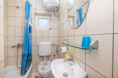 uma casa de banho com um lavatório, um WC e um espelho. em Apartments by the sea Podgora, Makarska - 6789 em Podgora