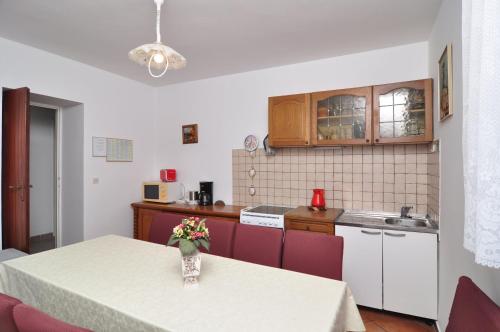 a kitchen with a table with a vase of flowers on it at Apartments by the sea Seget Vranjica, Trogir - 6597 in Seget Vranjica