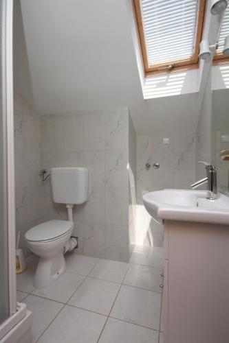 a white bathroom with a toilet and a sink at Apartments by the sea Mandre, Pag - 6507 in Kolan