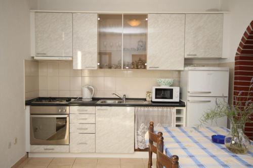 a kitchen with white cabinets and a table and a microwave at Apartments with a parking space Makarska - 6792 in Makarska