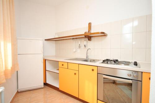 uma cozinha com armários amarelos e um frigorífico branco em Apartments by the sea Podgora, Makarska - 6664 em Podgora