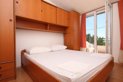 um quarto com uma cama com armários de madeira e uma janela em Apartments with a parking space Makarska - 6791 em Makarska