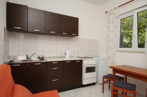 uma cozinha com armários castanhos, um lavatório e uma mesa em Apartments with a parking space Makarska - 6791 em Makarska