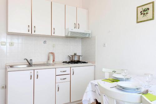 a kitchen with white cabinets and a sink and a table at Apartments by the sea Podgora, Makarska - 6671 in Podgora