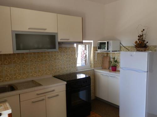 a kitchen with white cabinets and a white refrigerator at Apartments with a parking space Tar, Porec - 6943 in Tar