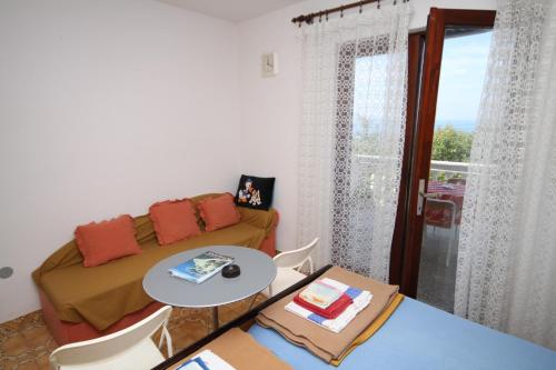 un soggiorno con divano, tavolo e finestra di Apartments and rooms by the sea Povljana, Pag - 6476 a Povljana (Pogliana)