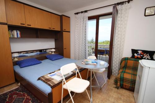 1 dormitorio con cama, mesa y balcón en Apartments and rooms by the sea Povljana, Pag - 6476, en Povljana