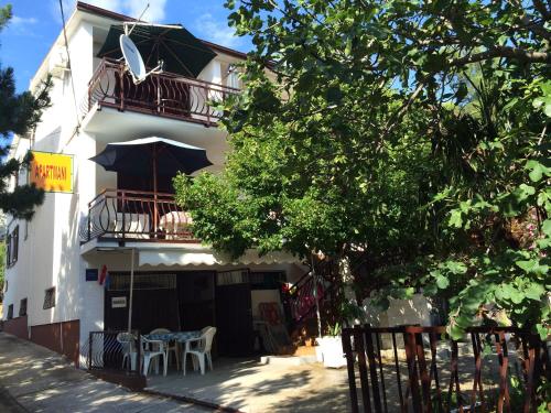 a white building with tables and umbrellas in front of it at Apartments by the sea Starigrad, Paklenica - 6621 in Starigrad