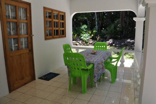 een groene tafel en stoelen op een patio bij La Colombe D'Or in Grand'Anse Praslin