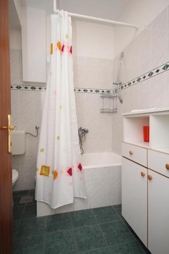 a bathroom with a shower curtain and a bath tub at Apartments with parking space Makarska - 6693 in Makarska
