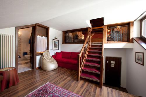 a living room with a staircase and a red couch at Hotel Baita Clementi in Bormio